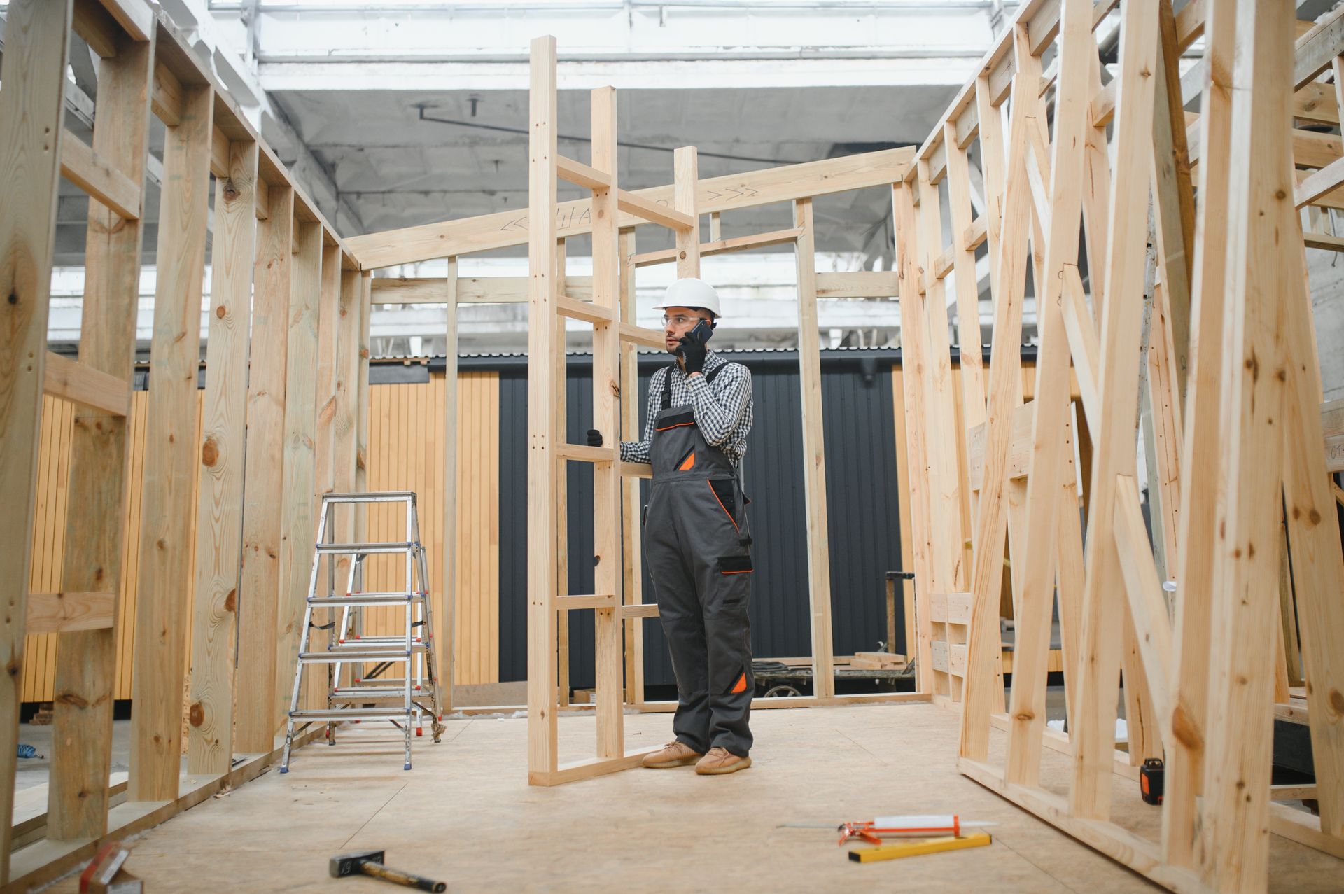 A man is standing in a wooden frame of a house under construction.