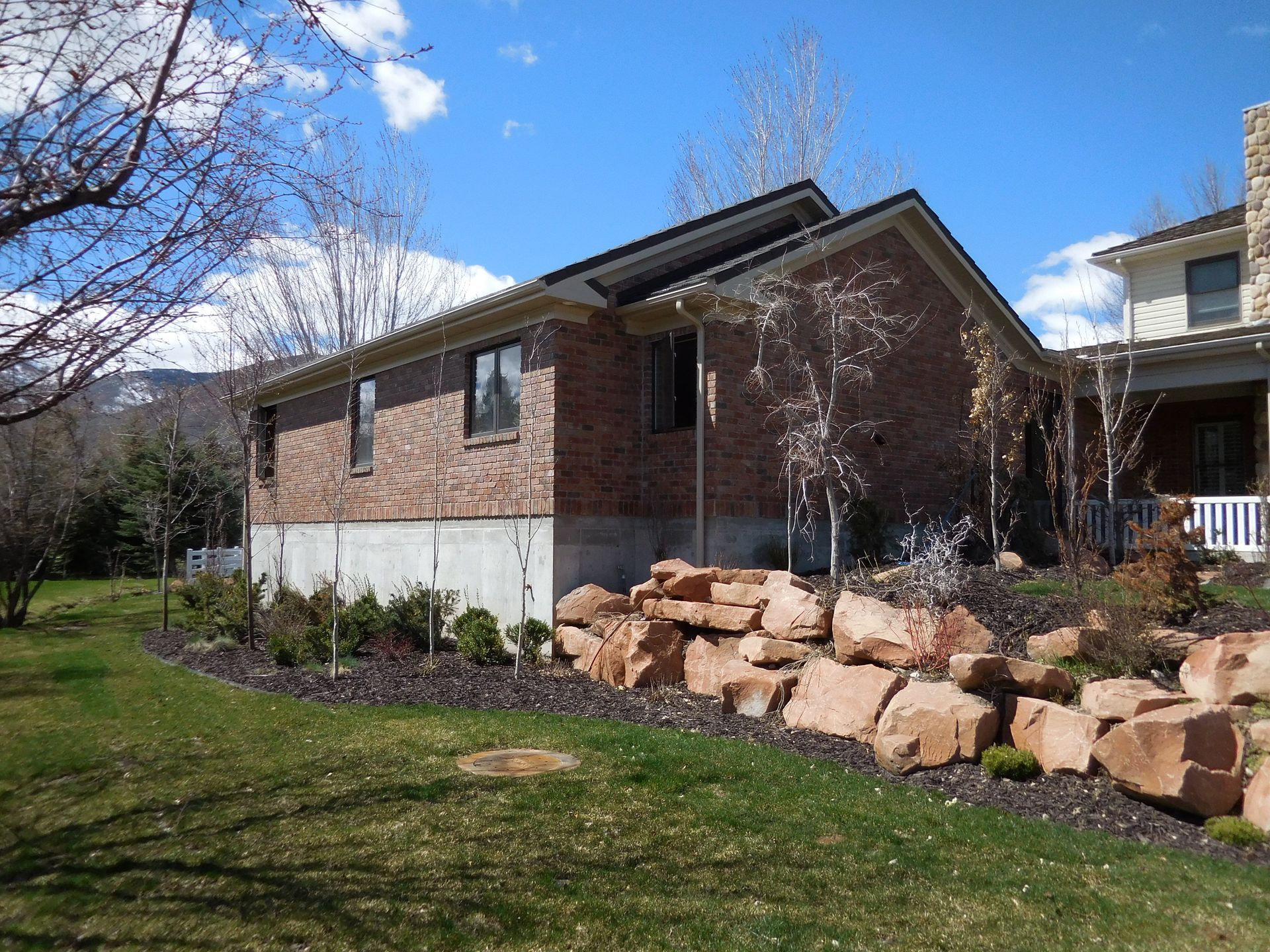 A brick house with a large rock wall in front of it