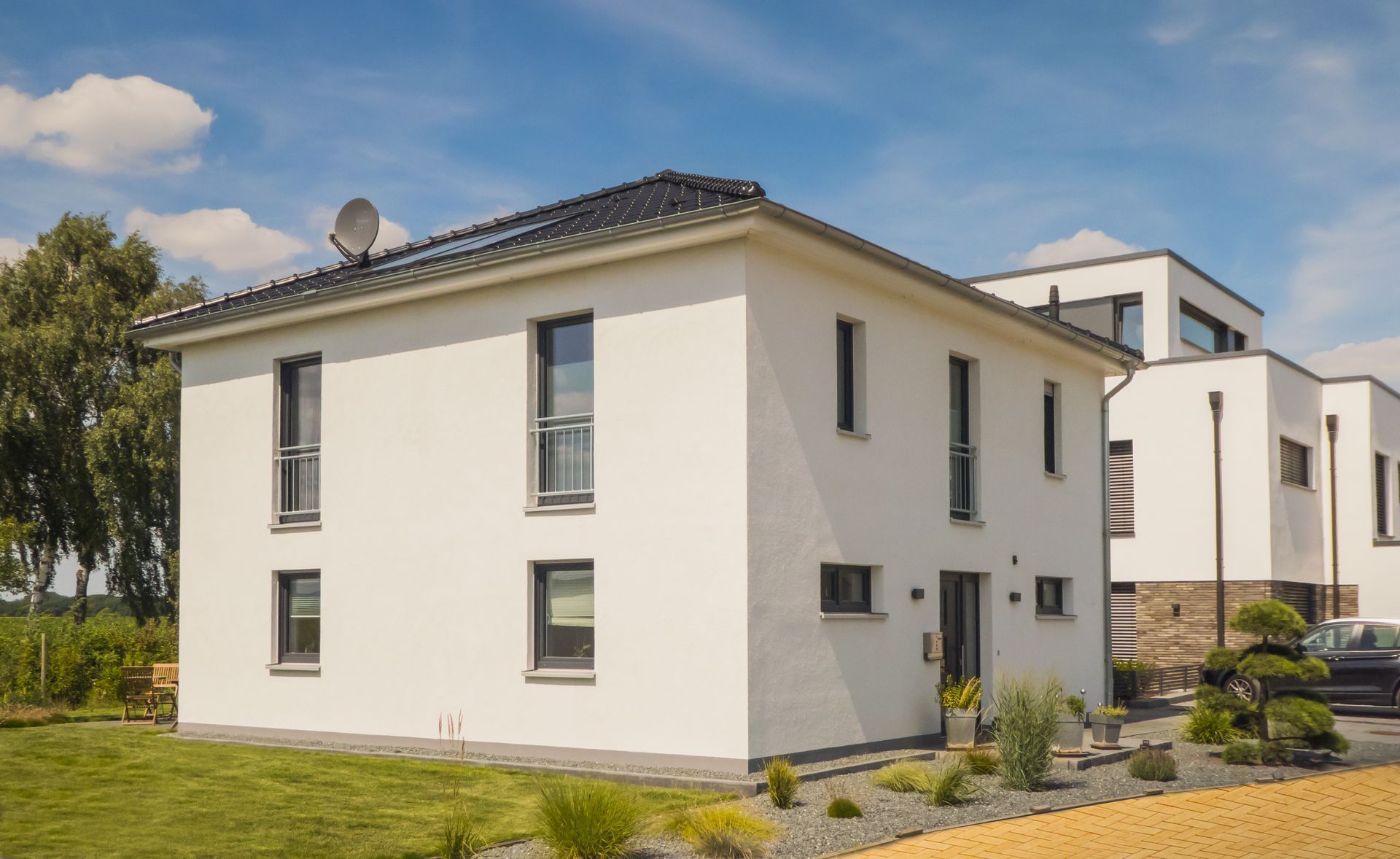 ein weißes Haus mit vielen Fenstern und einer Satellitenschüssel auf dem Dach.