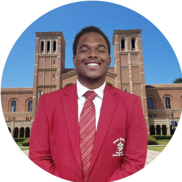 Man in red blazer and tie smiles in front of UCLA Royce Hall.