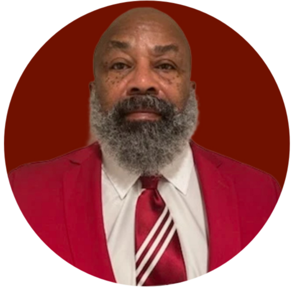 Man in red suit, white shirt, and patterned tie, gray beard, with fraternity logo in the top right.