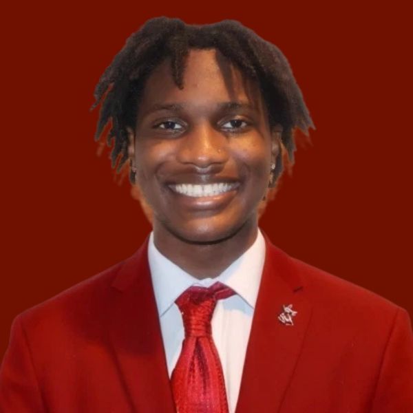 Smiling young Black man in red suit and tie.