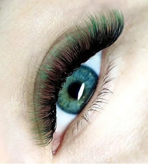 A close up of a woman 's eye with green eyelashes.