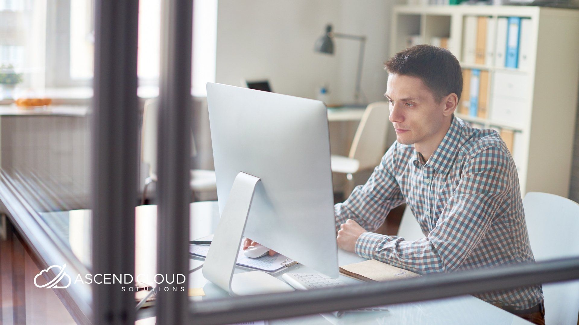 A man is sitting at a desk in front of a computer.