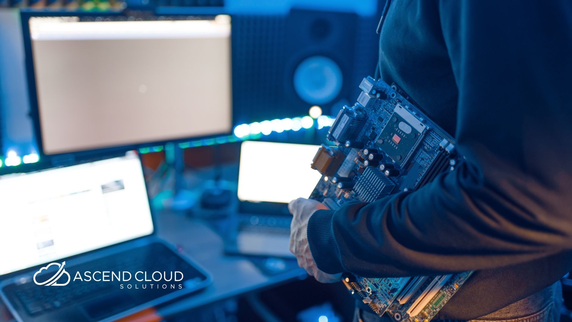 A man is holding a motherboard in front of a computer.