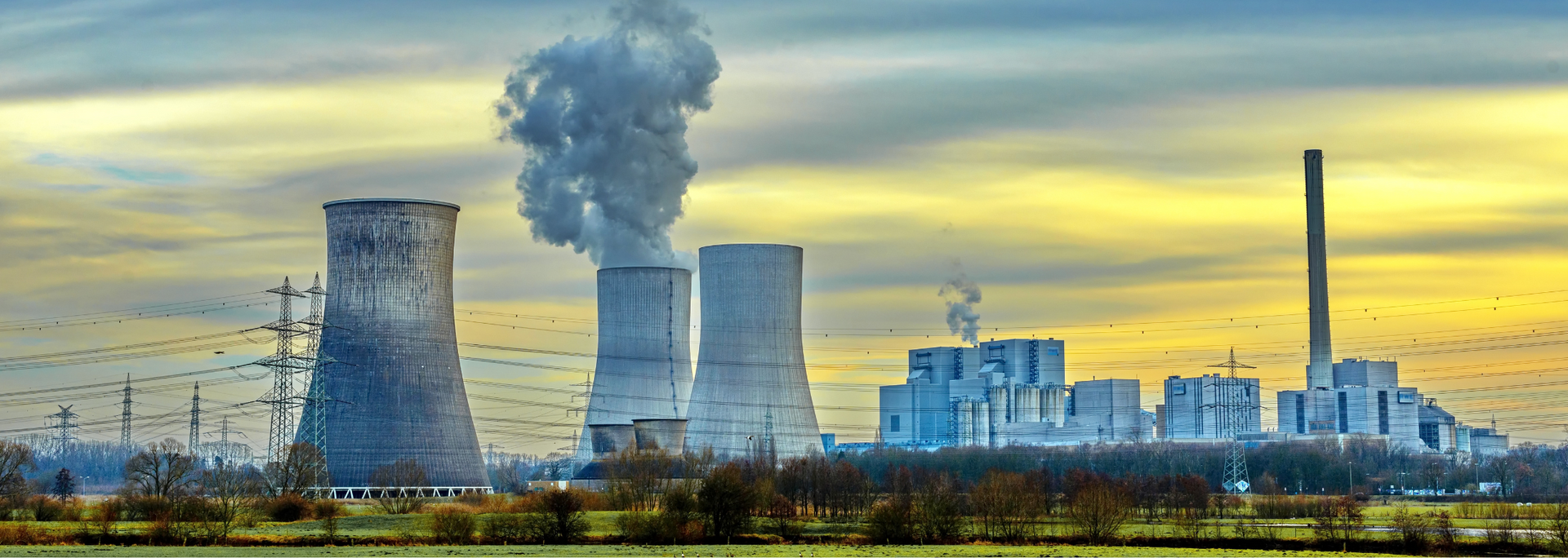 A nuclear power plant with smoke coming out of the cooling towers.