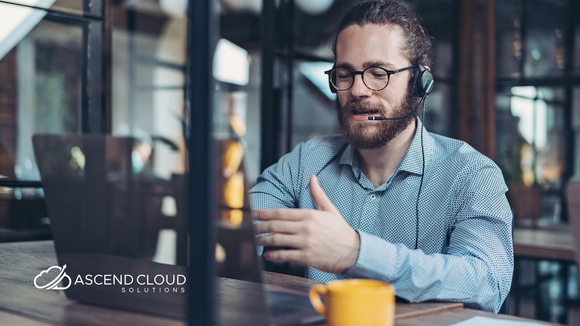 A man wearing a headset is sitting at a table with a cup of coffee.