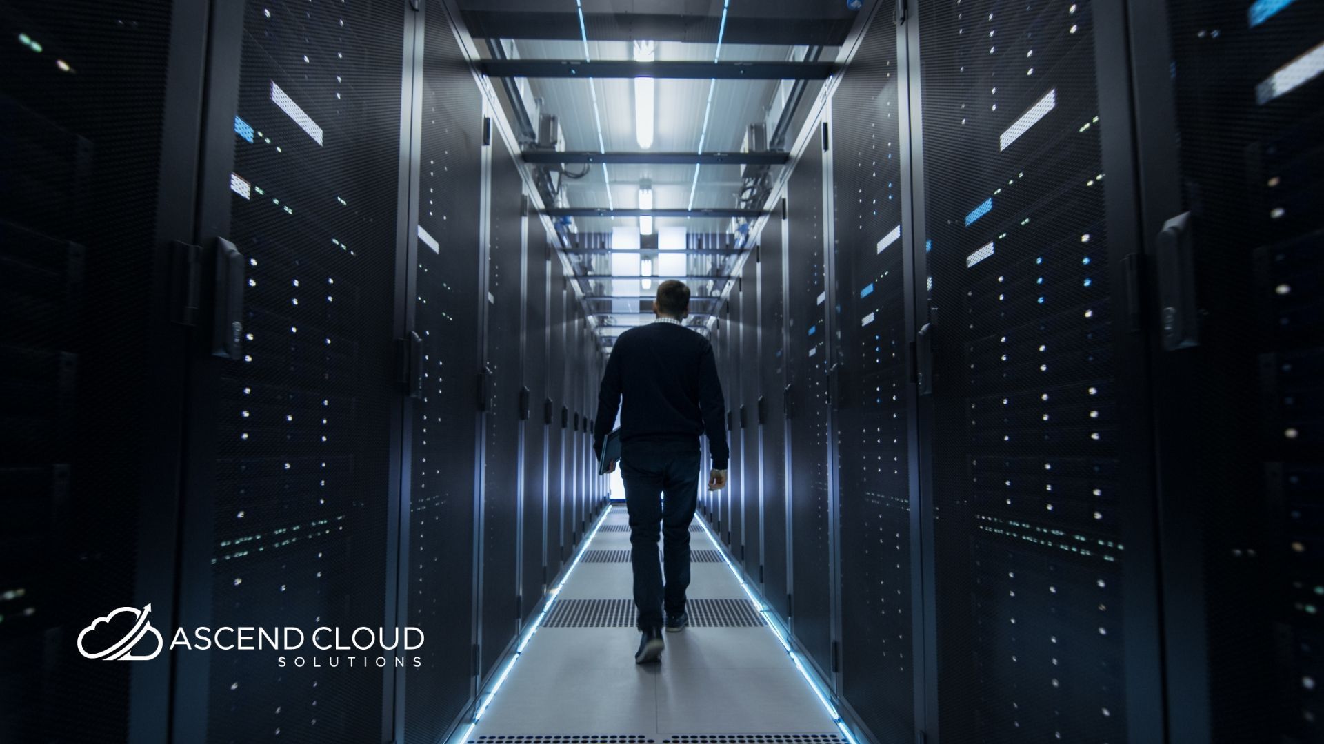 A man in a suit is walking through a server room.