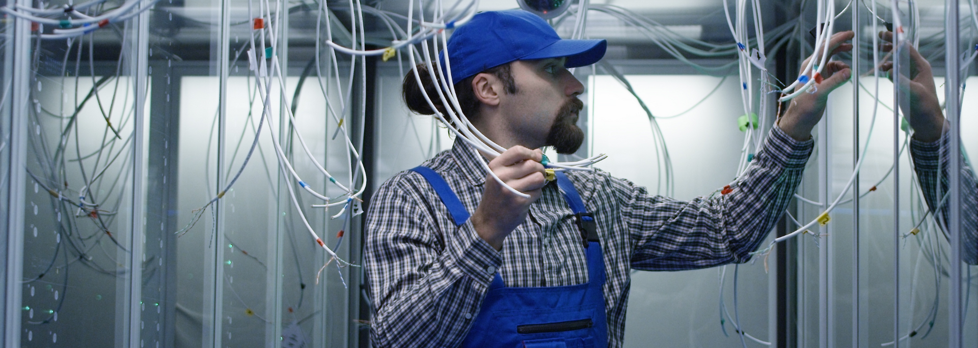 Picture of a IT technician amongst cables, looking perplexed