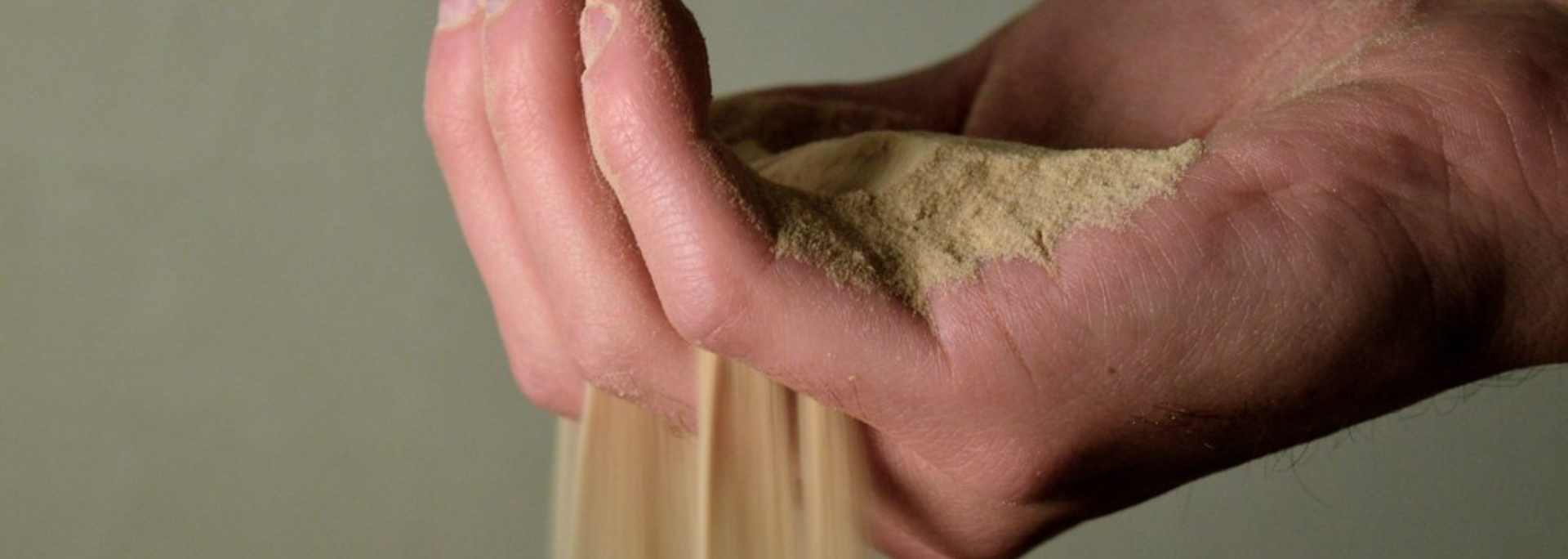 Picture of sand slipping through someone's fingers.