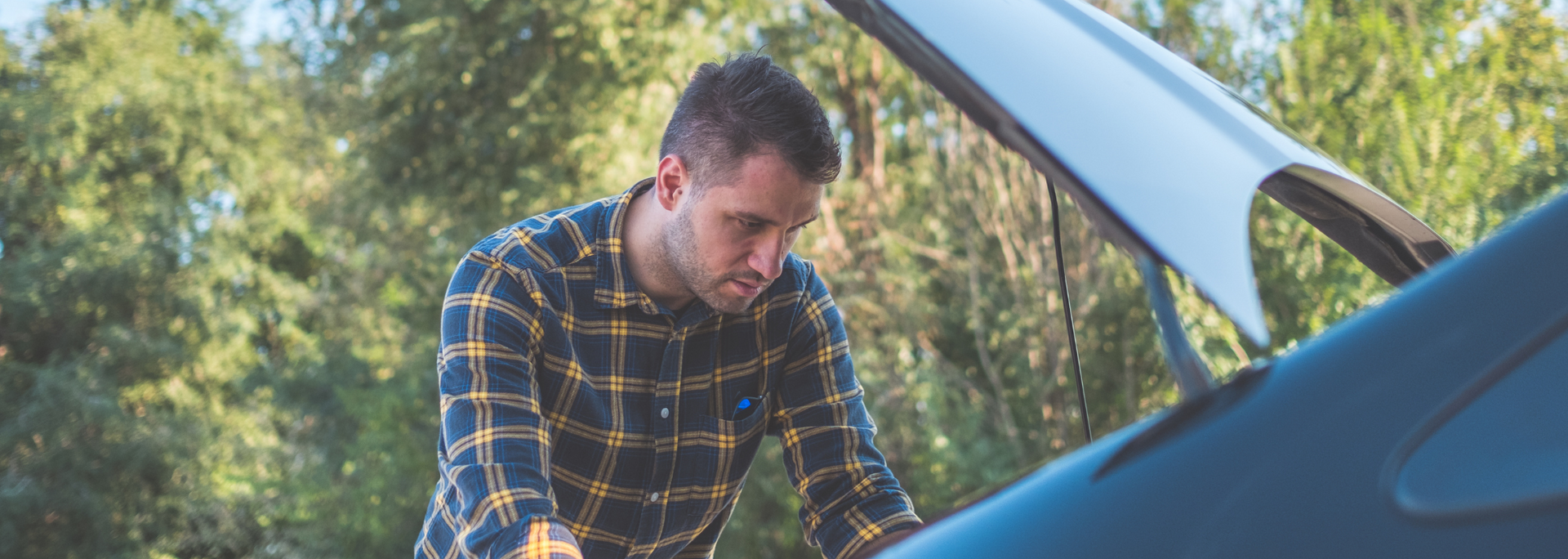 Picture of someone looking under a bonnet of a car.