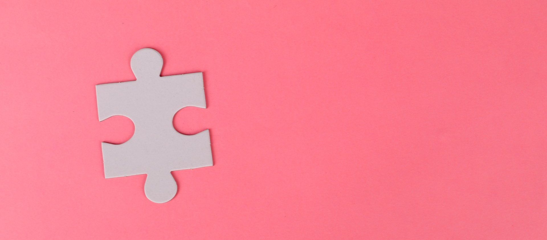 A white puzzle piece on a pink background.