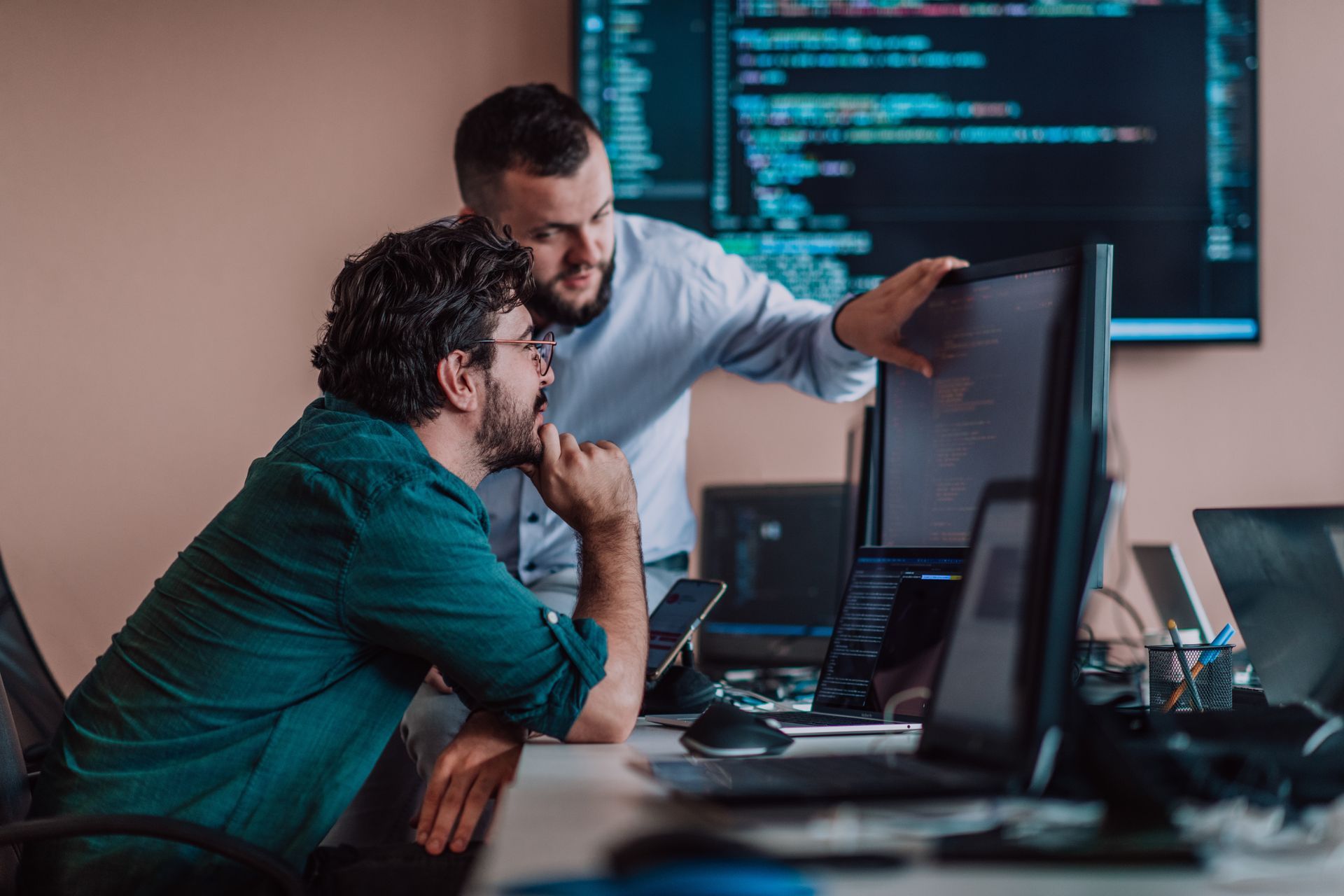 Two men are looking at a computer screen in an office.