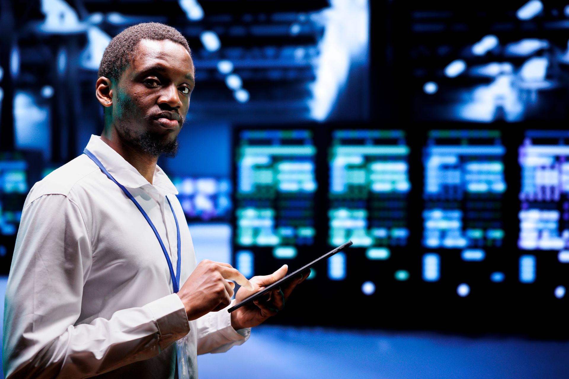 A man is holding a tablet in a server room.