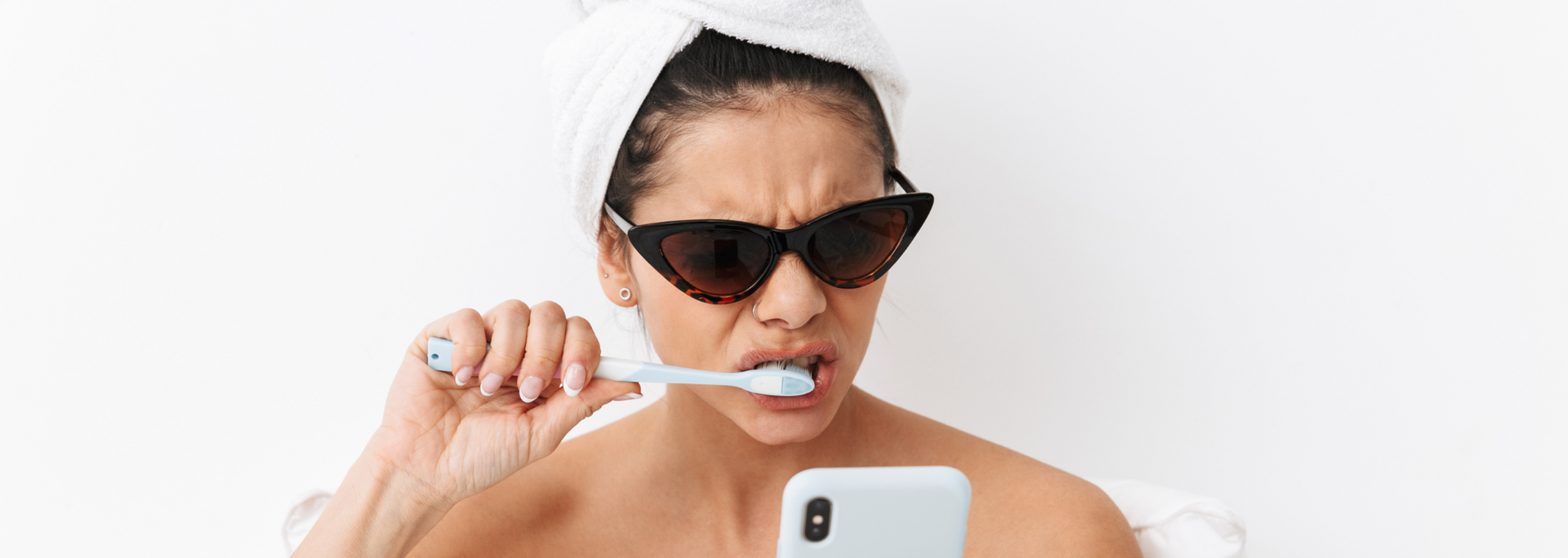 Picture of a woman brushing her teeth while looking at her phone..