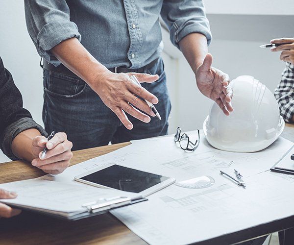 hands of construction manager above table and white helmet