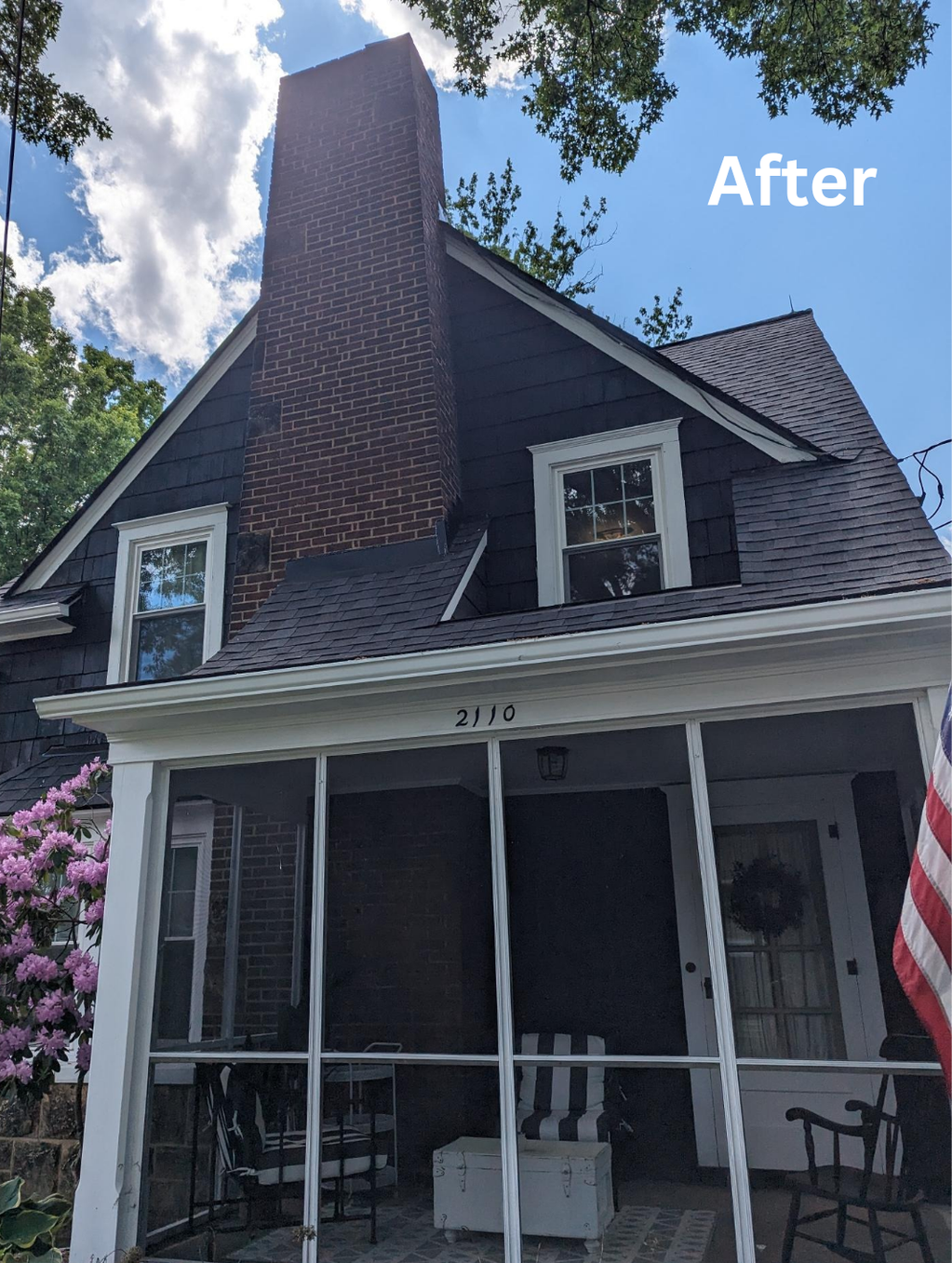 After view of a house with dark shingle roof, tall brick chimney, and front porch under blue sky