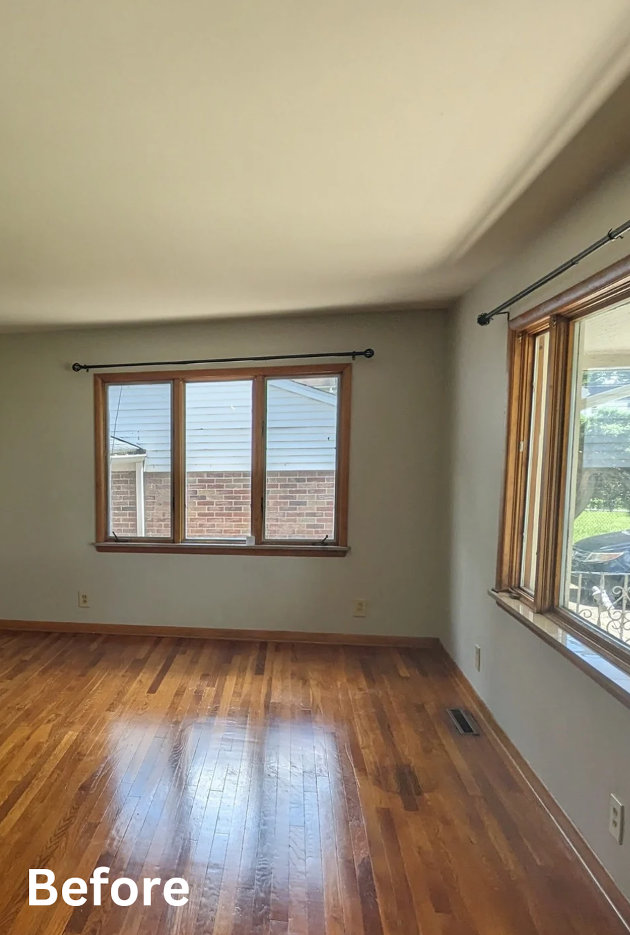 Empty room with hardwood floors, gray walls, and large windows, labeled “Before”