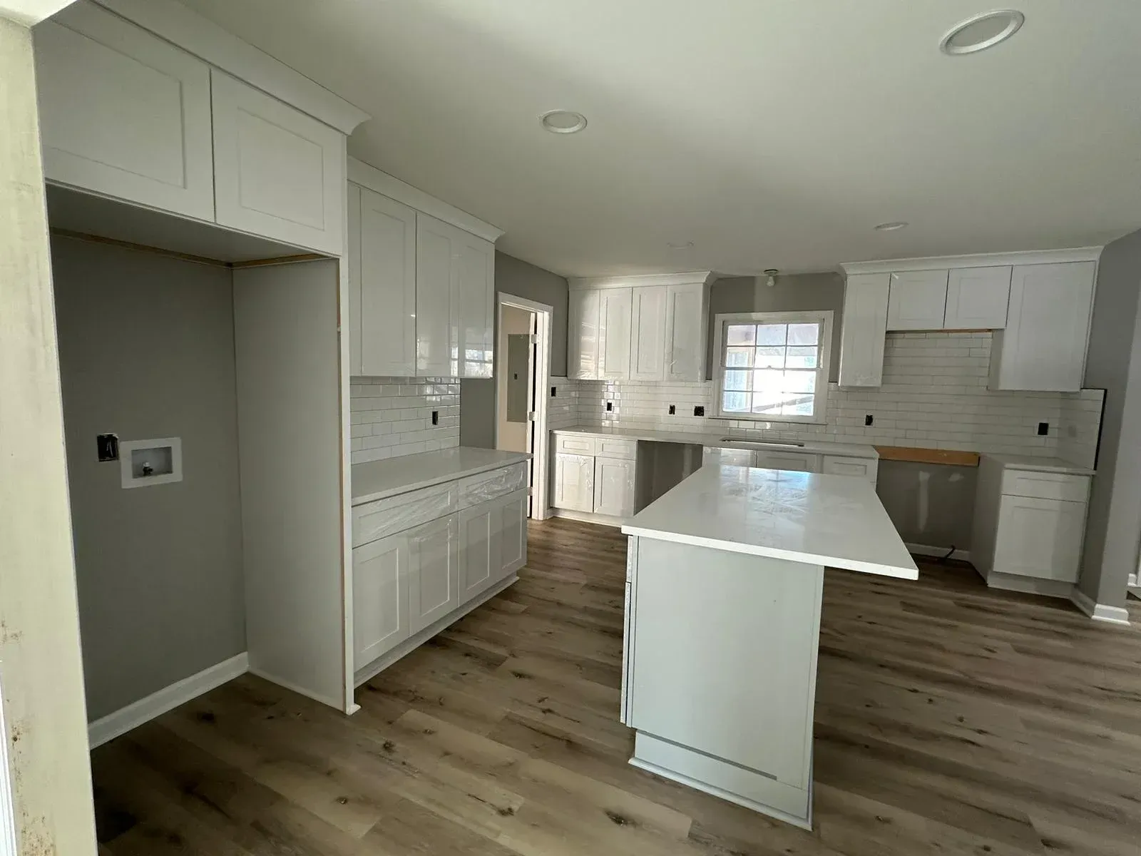A kitchen with white cabinets and a large island in the middle of the room.