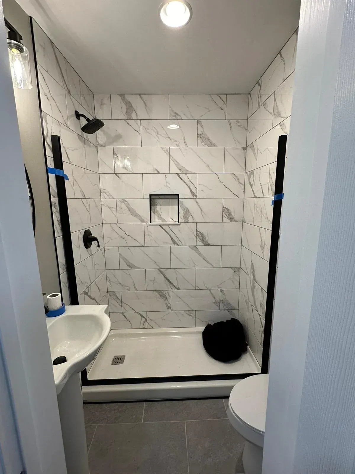A bathroom with a shower , sink , toilet and mirror.