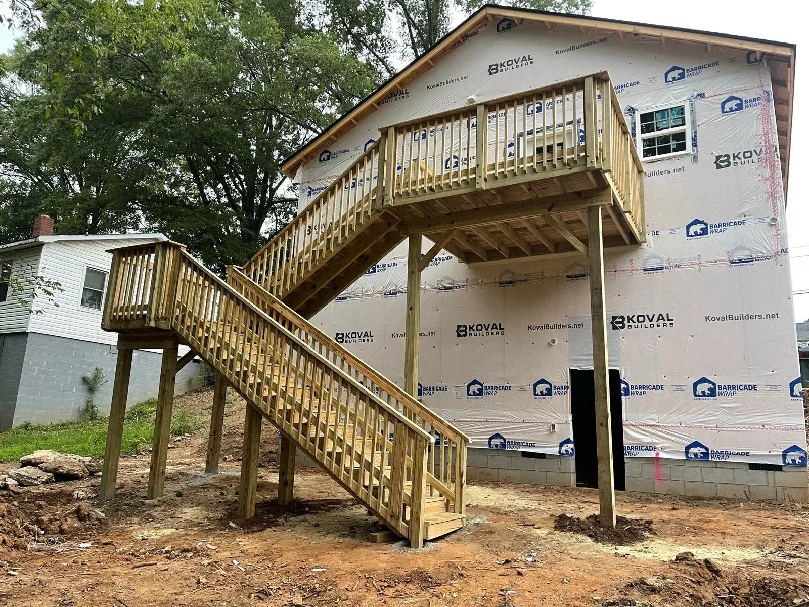 A wooden deck with stairs leading up to it is being built on the side of a house.