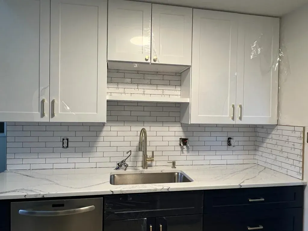 A kitchen with white cabinets and a stainless steel sink.