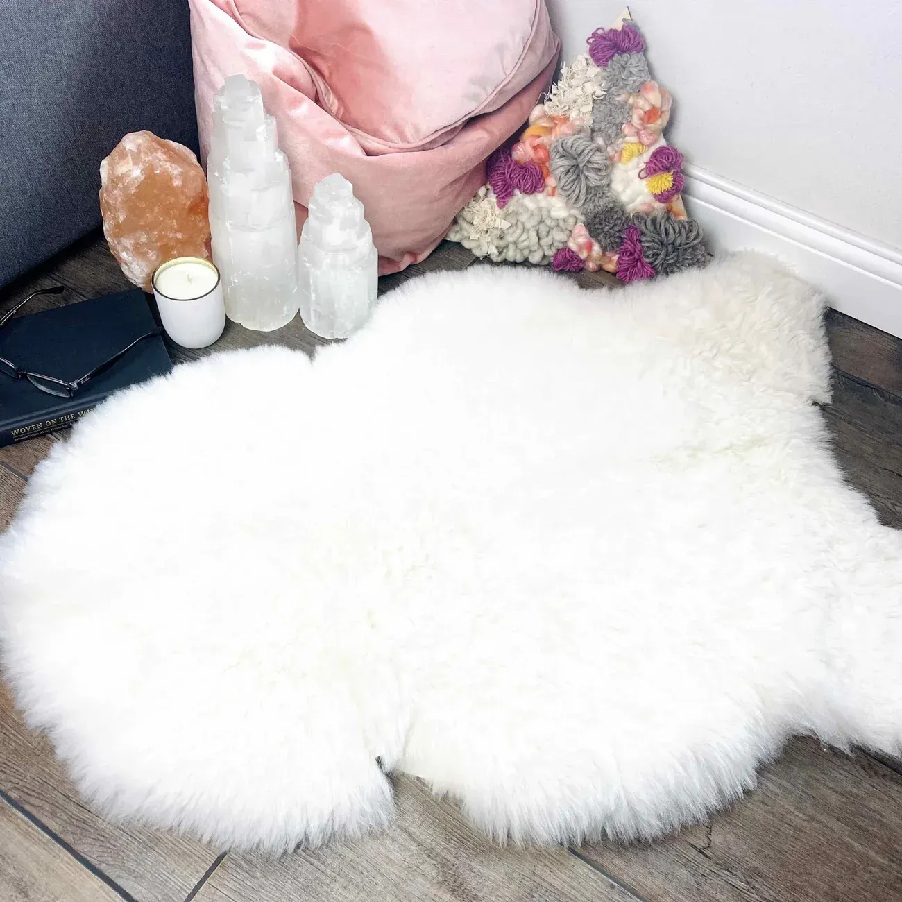 White sheepskin rug on wood floor, with crystals, a pink beanbag chair, and decorative pillow.