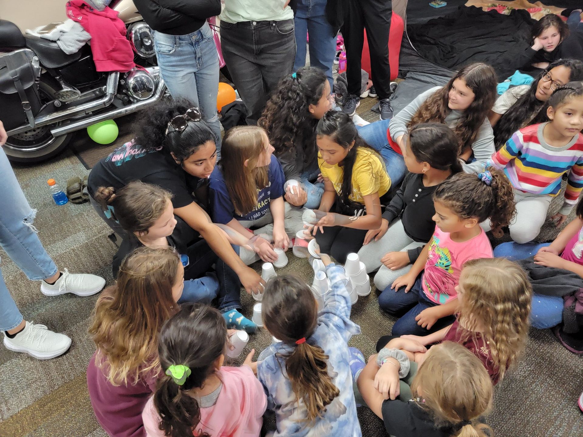 A group of children are sitting on the ground in a circle.