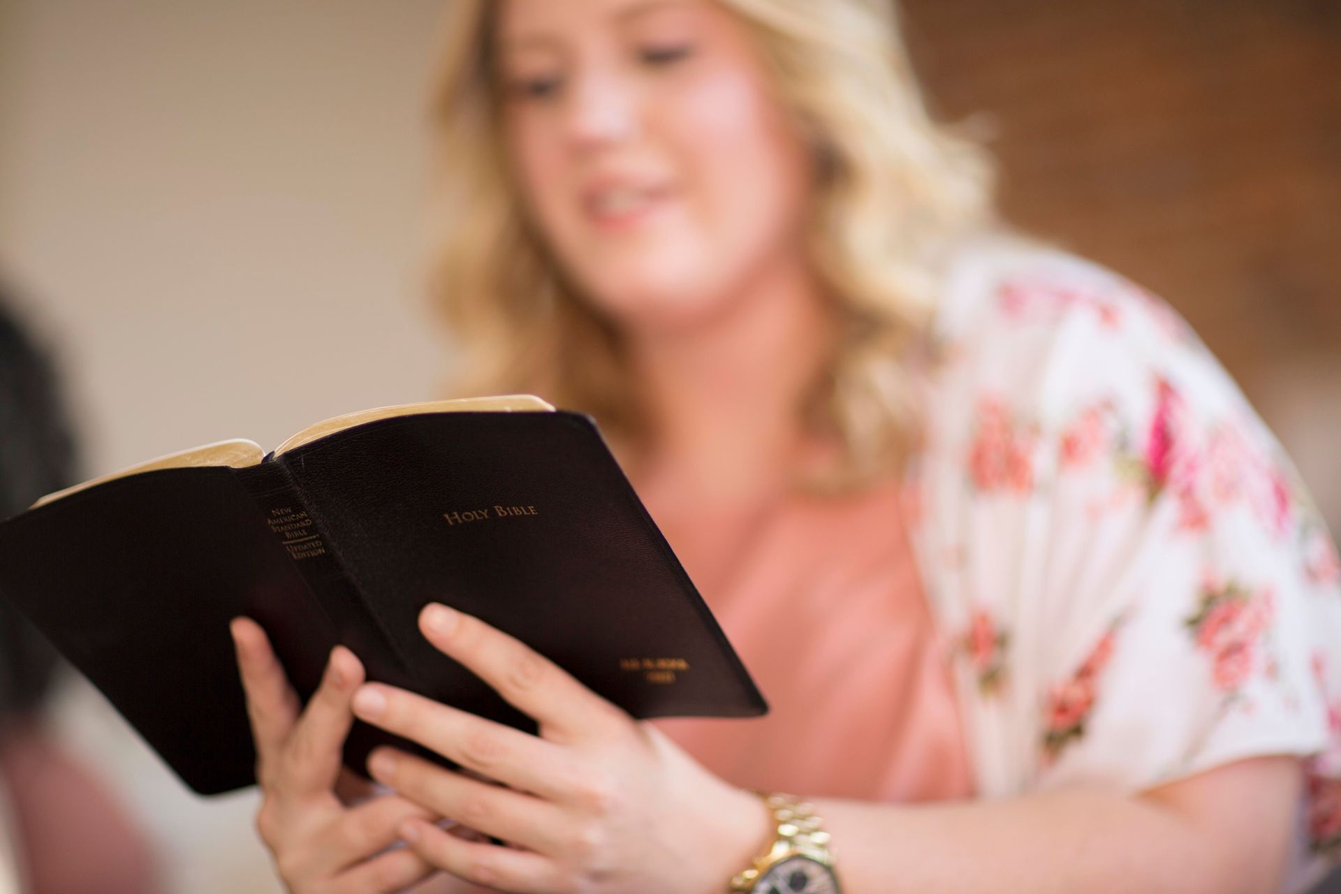 A woman is holding a bible in her hands and reading it.