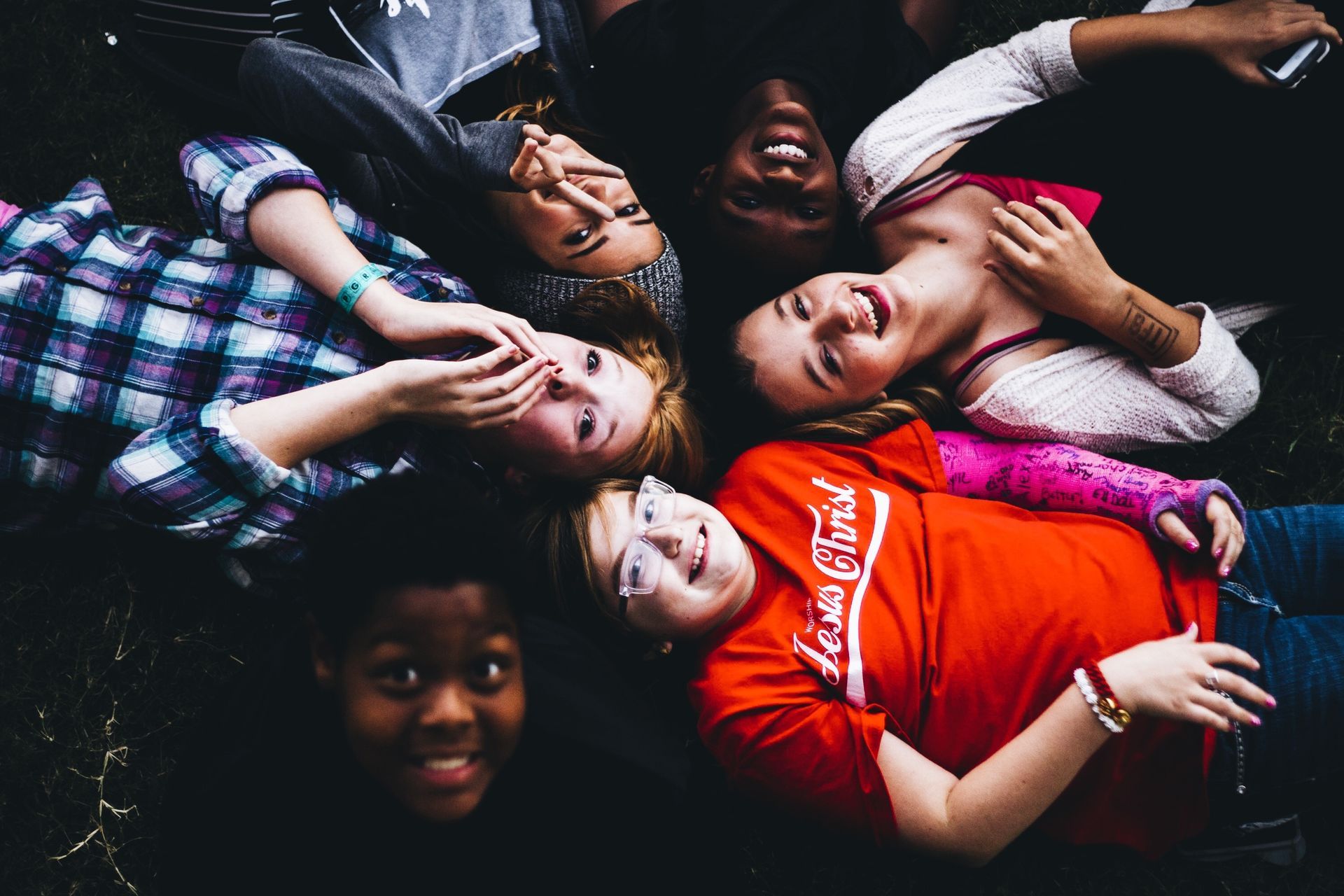 A group of young people are laying on the ground in a circle.