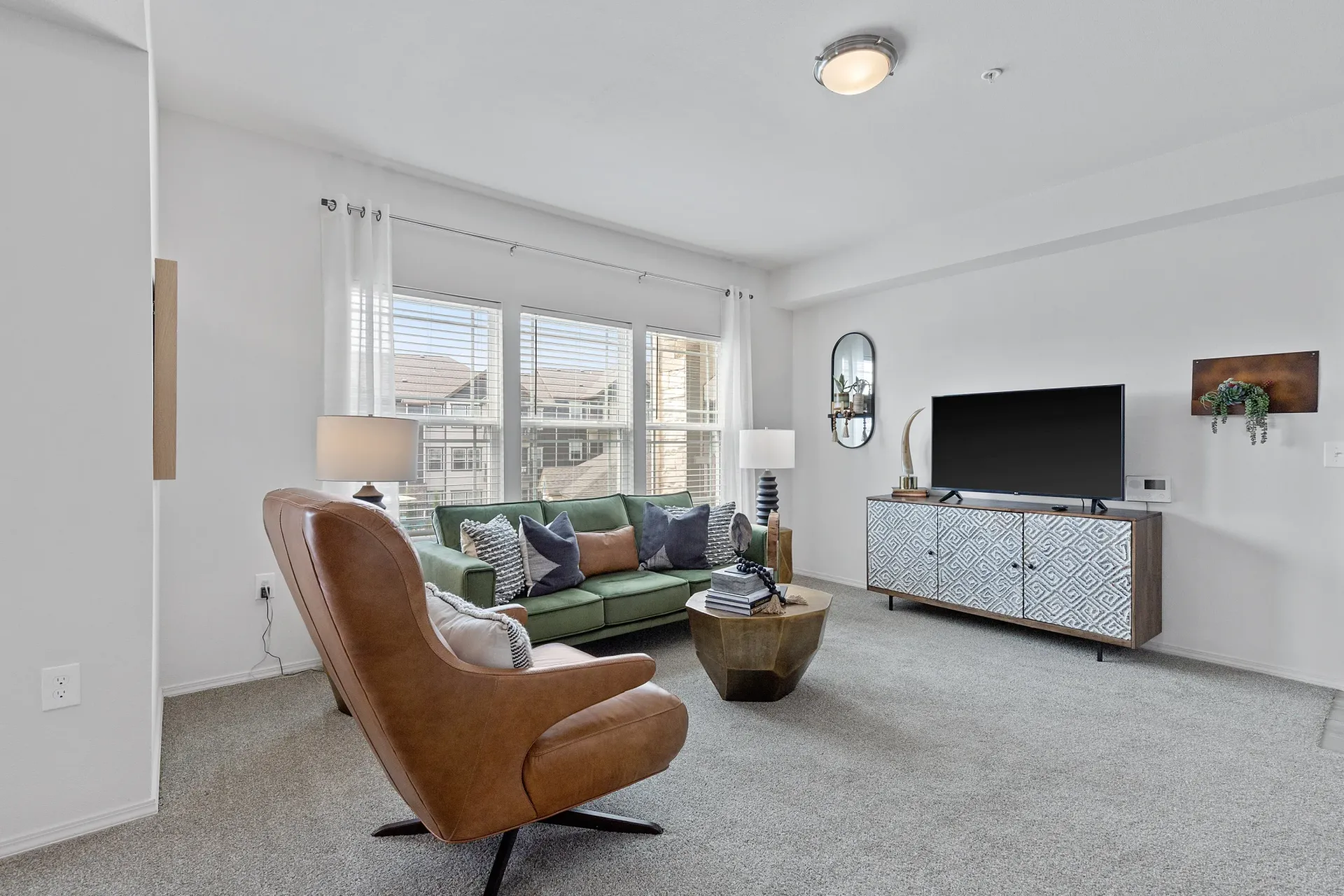 Stylish living room featuring a green sofa, armchair, coffee table, and a TV stand with a TV.