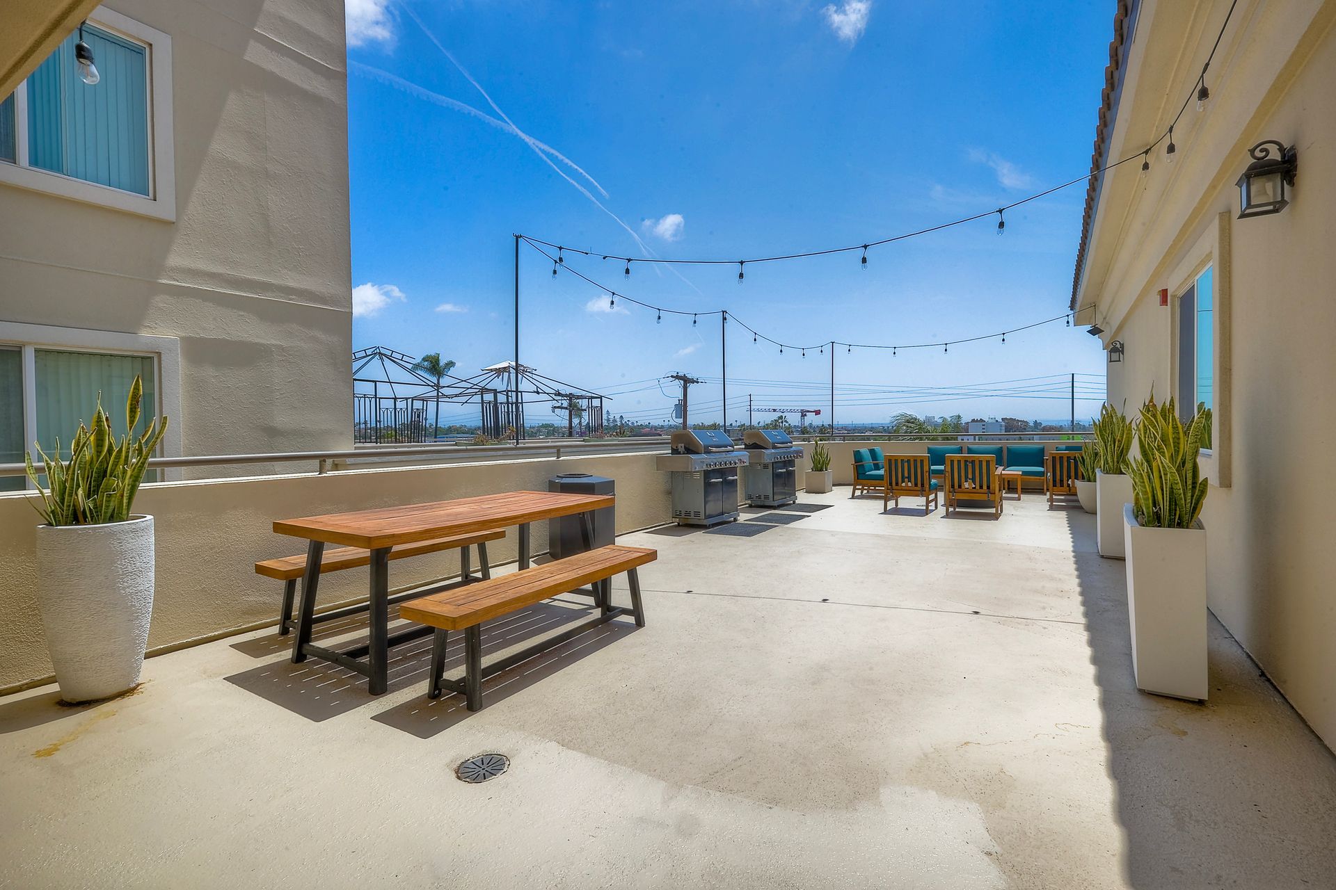 Photo of an outdoor rooftop area with a bench in the foreground and the barbecue area in the background