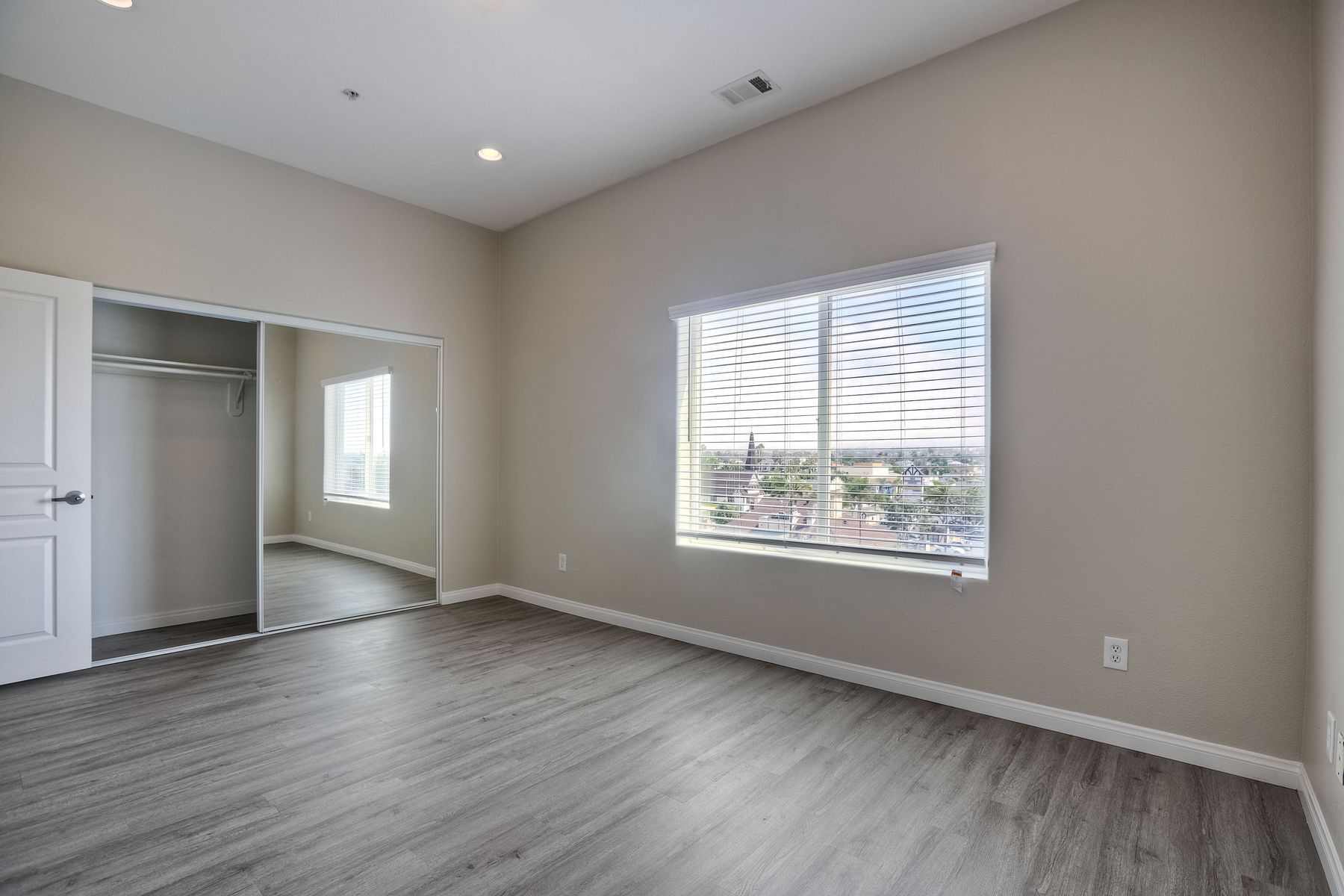 Photo of a room showing a mirrored-door closet and a wide window