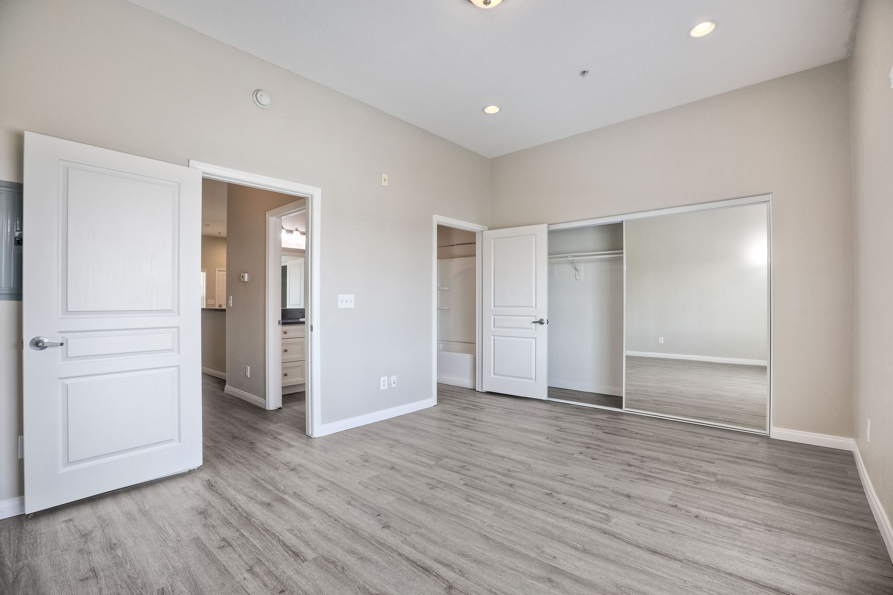 Photo of a bedroom with a high ceiling and mirrored-sliding closet doors
