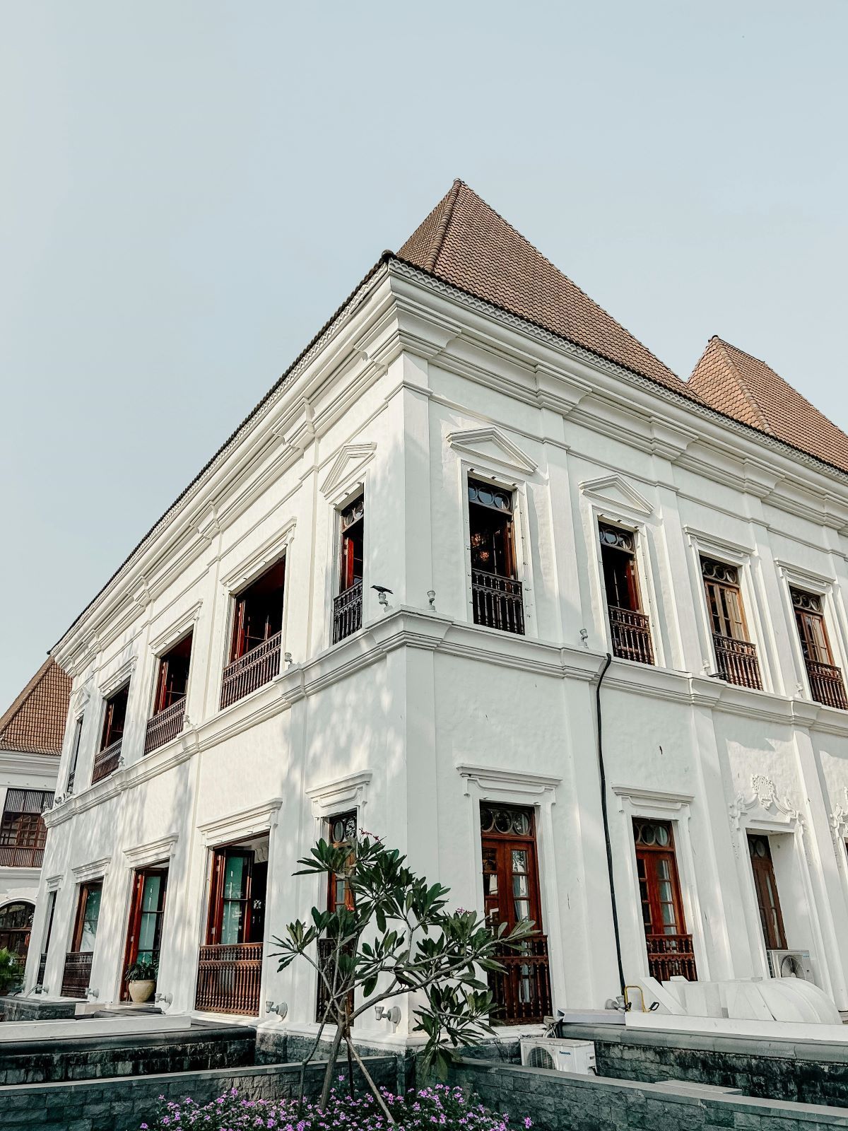 A large white building with a brown roof and a lot of windows.
