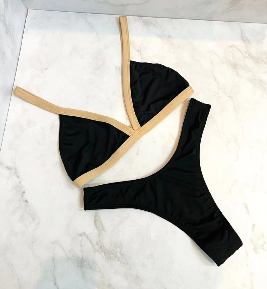 Bikini negro y tostado sobre una superficie de mármol.