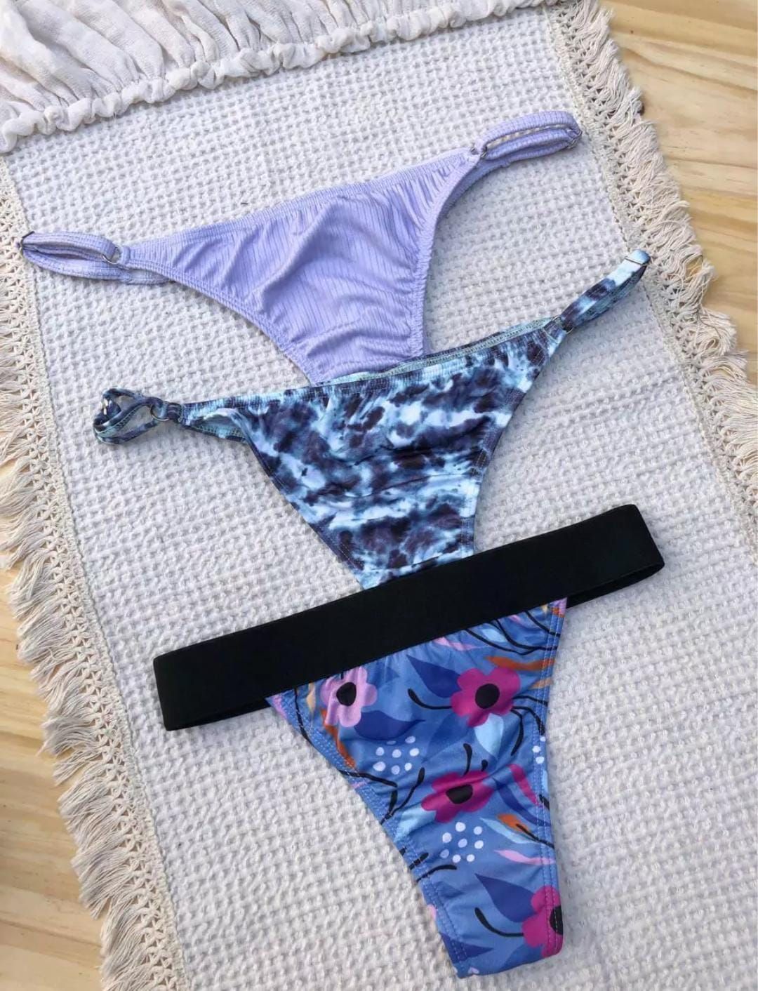Tres braguitas de baño estilo tanga sobre una esterilla tejida.