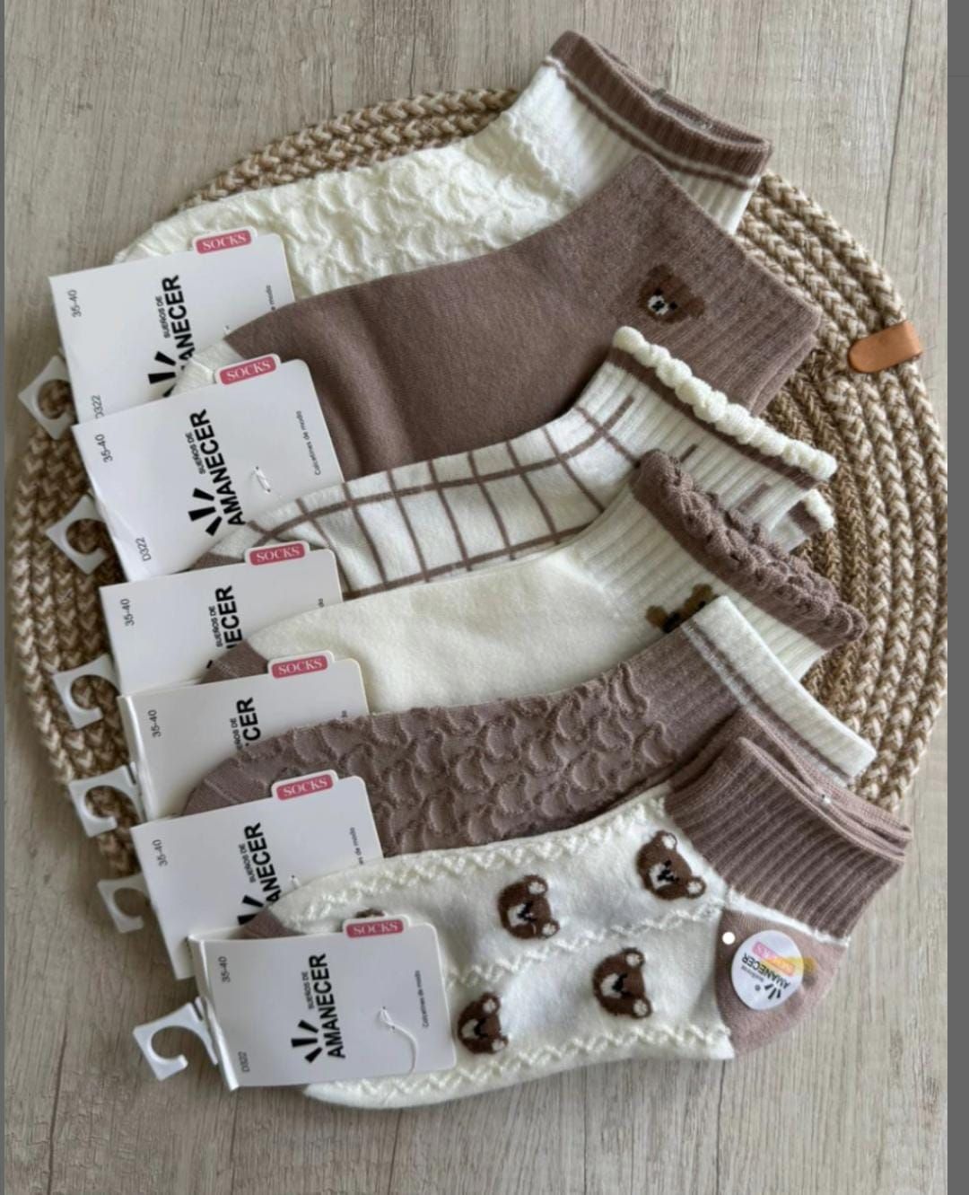 Calcetines tobilleros surtidos en tonos neutros, incluidos marrón, blanco y crema, dispuestos sobre una estera tejida.