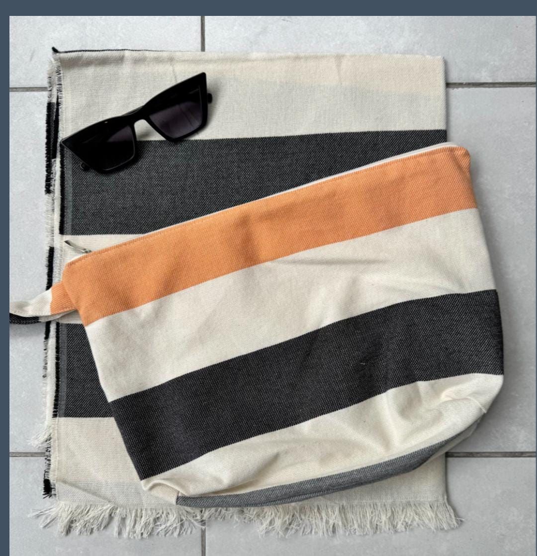 Toalla y bolsa con rayas negras y naranjas, gafas de sol encima.