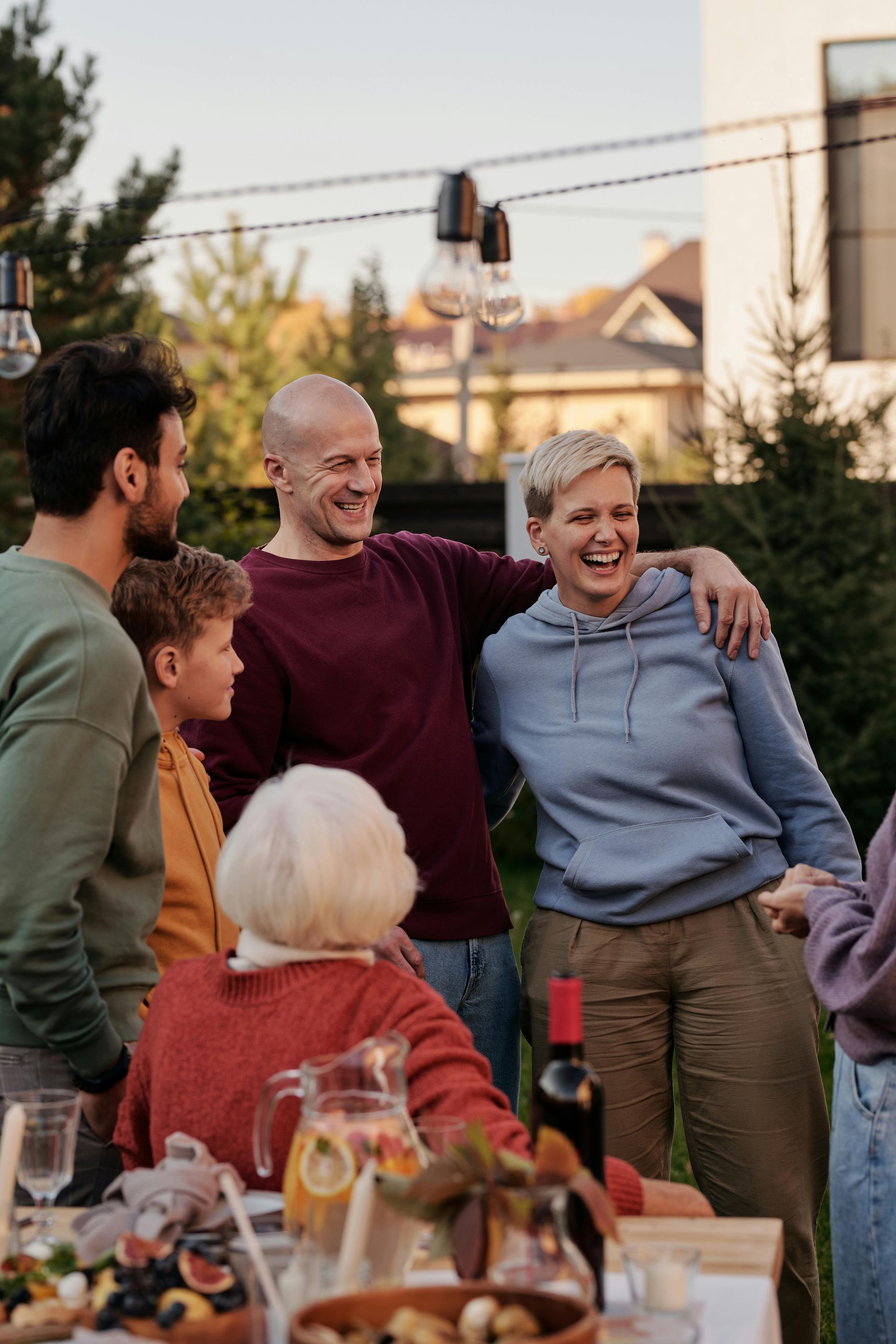 Family loading luggage into a car trunk; smiling people gather outdoors. 