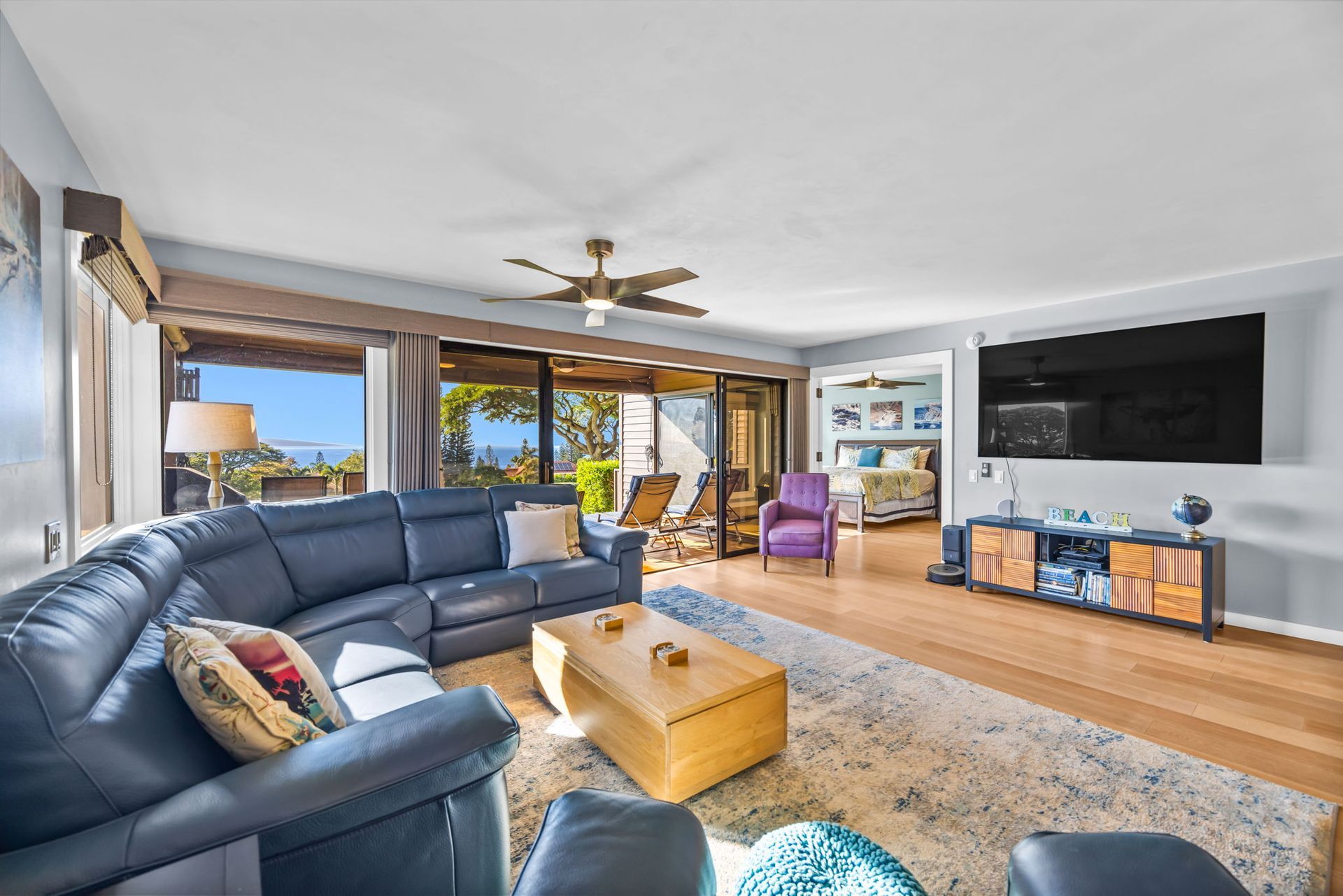 Living room with a large navy sectional, wooden coffee table, purple armchair, and wall-mounted television.