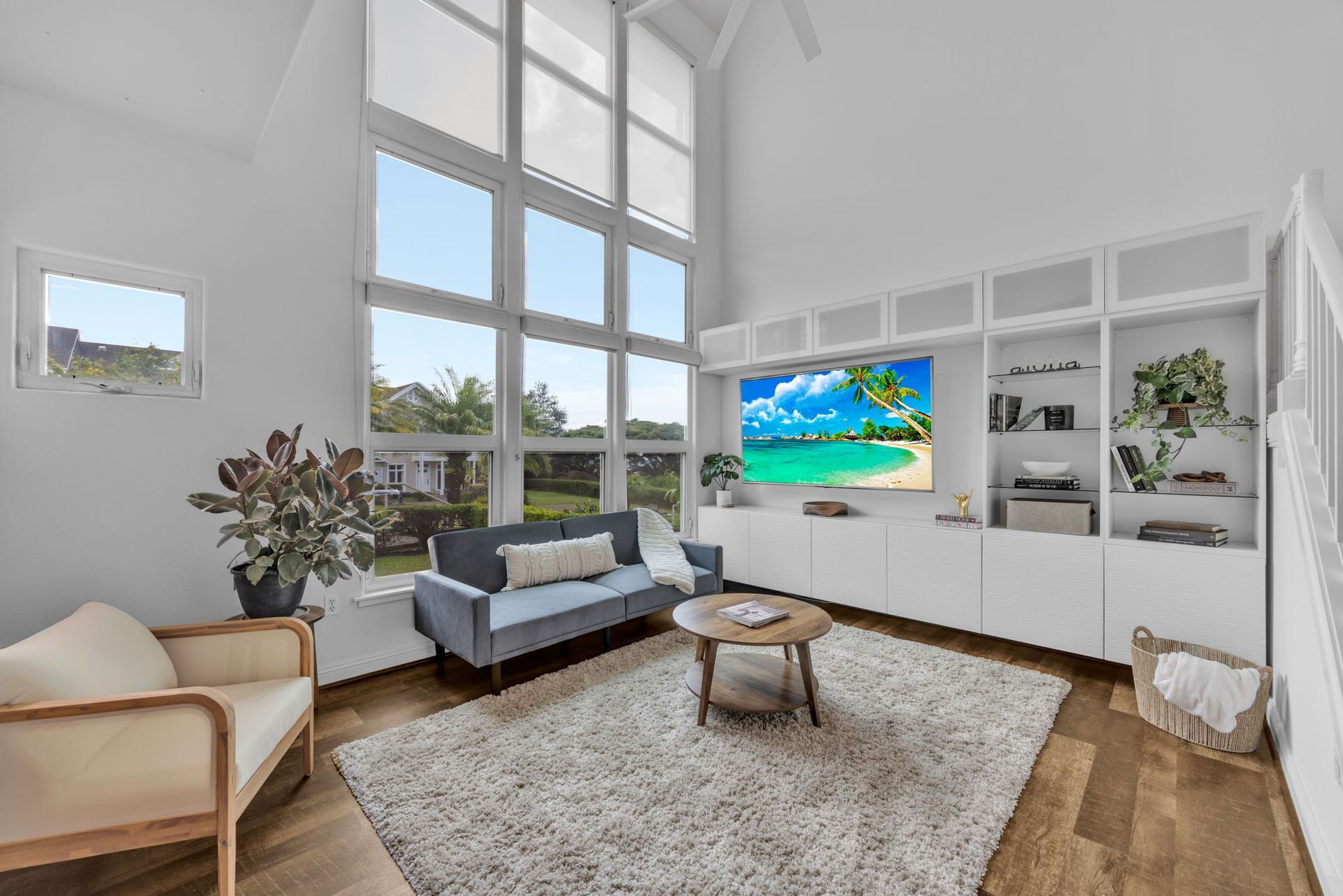 A living room with a beige armchair, a gray sofa, a wood coffee table, a shaggy rug, and a wall of white built-in shelves.
