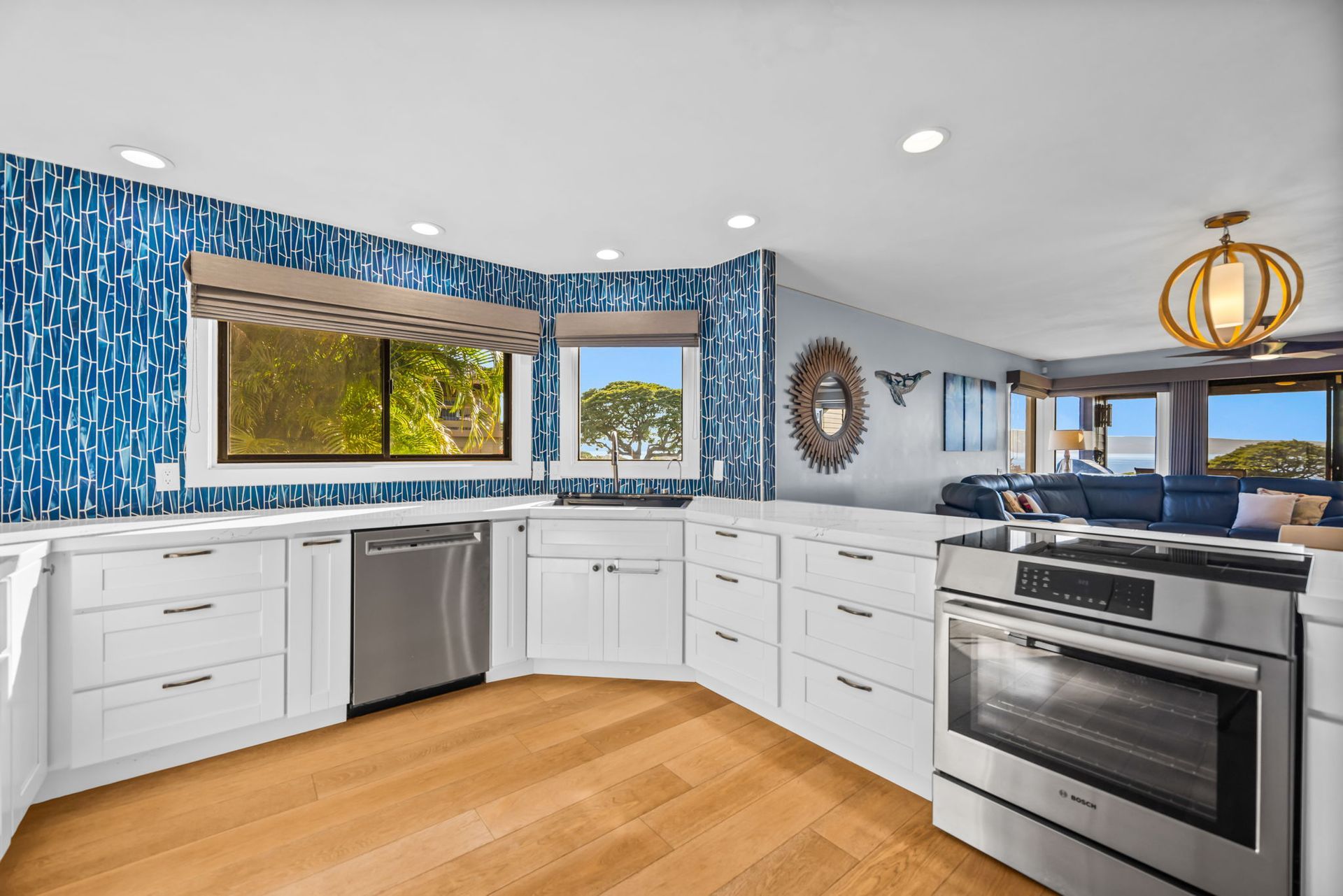 A modern kitchen with white cabinets, stainless steel appliances, and a blue patterned tile backsplash.