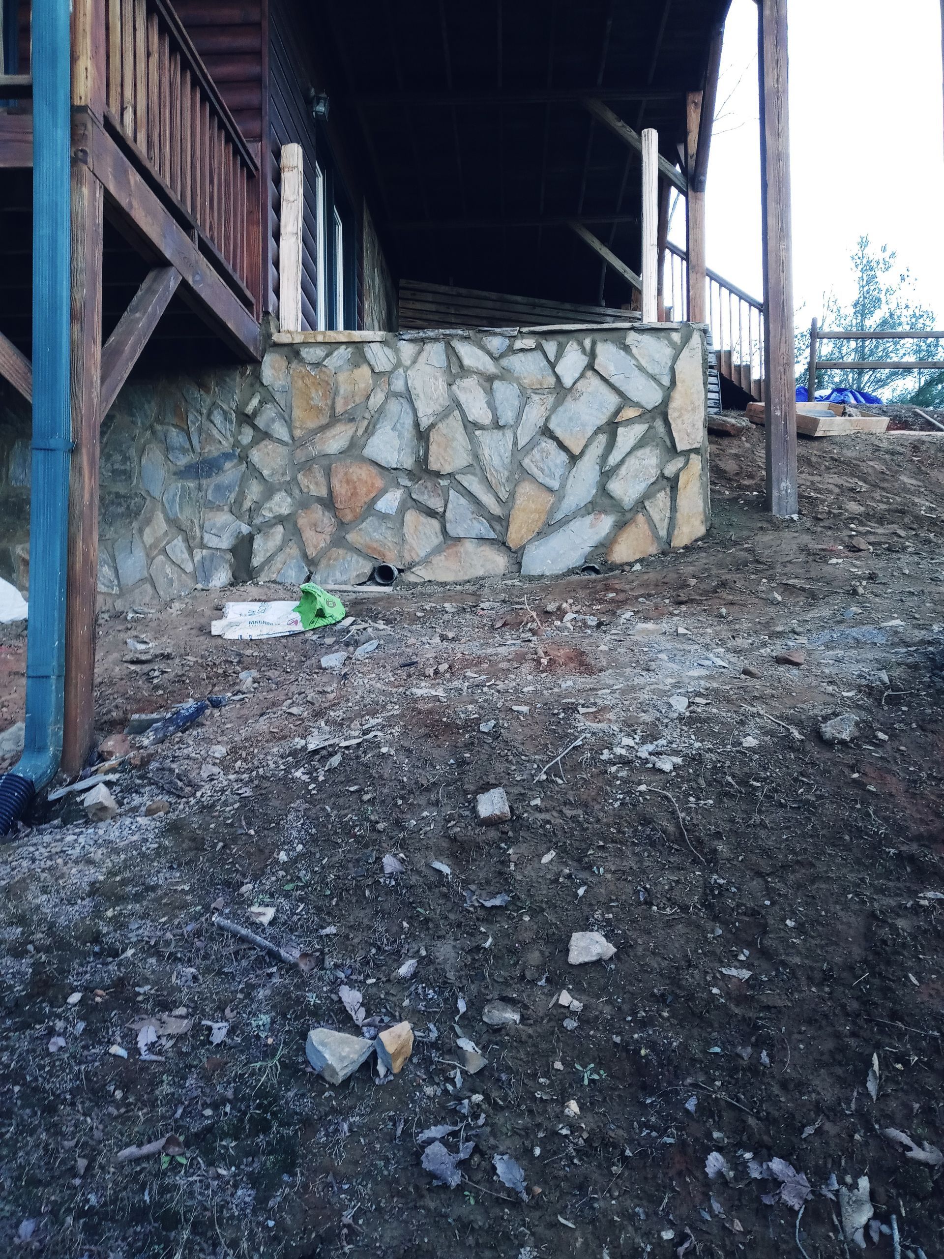 A stone wall is being built in front of a house