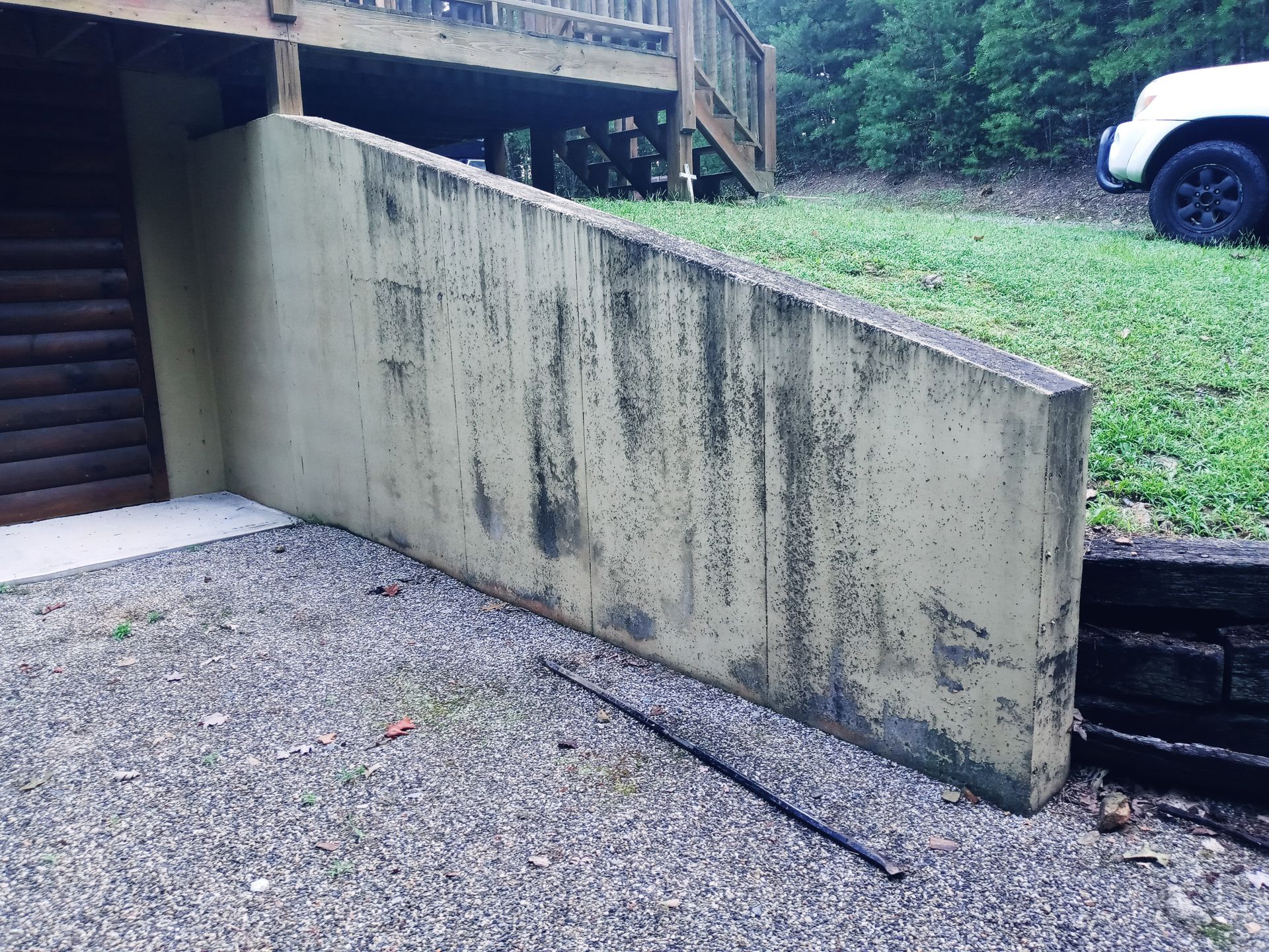 A white truck is parked next to a concrete wall