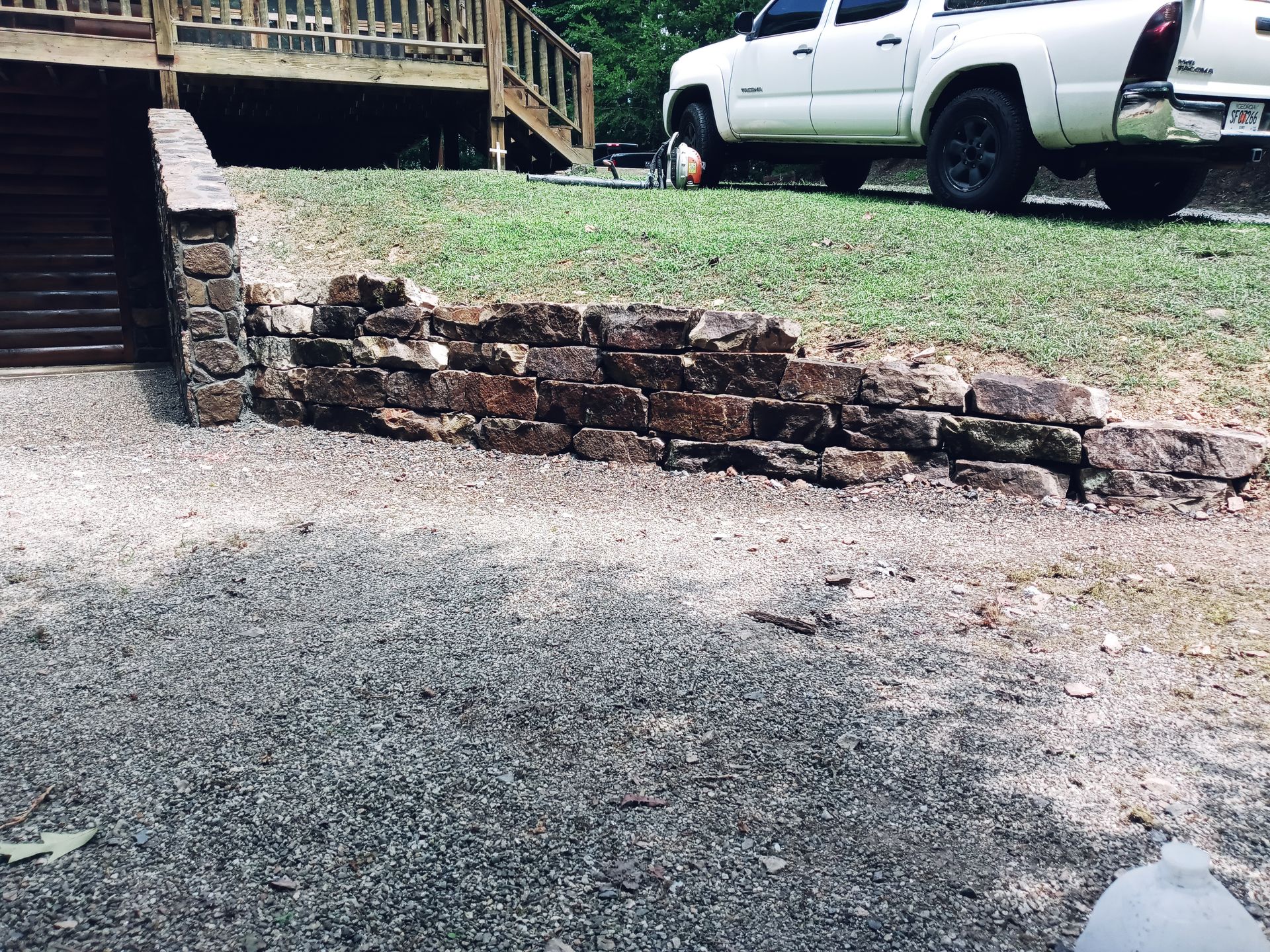 A white truck is parked in front of a stone wall.
