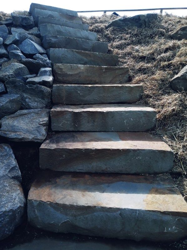 A set of stone stairs going up a hill surrounded by rocks