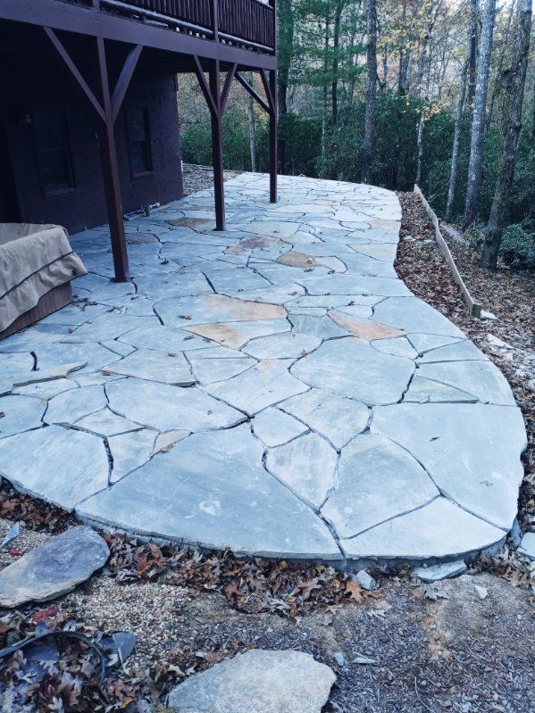 A large stone patio with a wooden deck in the background.