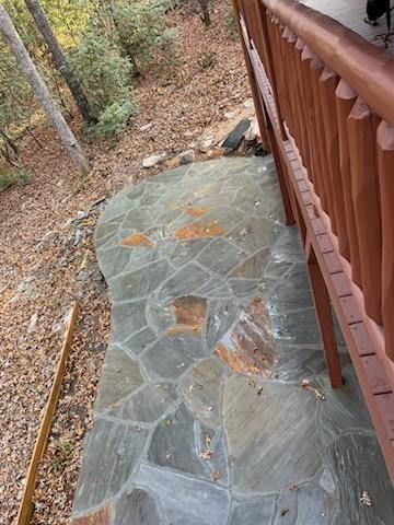 A stone walkway leading to a wooden deck with a wooden railing.