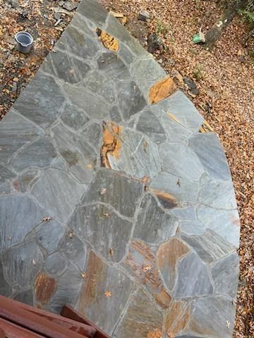 A stone walkway is being built next to a wooden deck.
